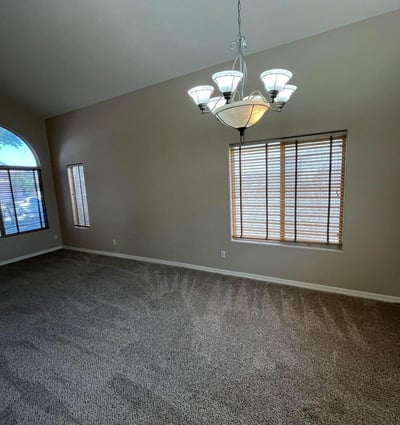 The expansive formal living area features dramatic vaulted ceilings, oversized picture windows, plush carpeting, and flexible space perfect for entertaining or everyday living.