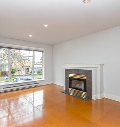 Spacious living area featuring a large window and a classic fireplace, perfect for customization.