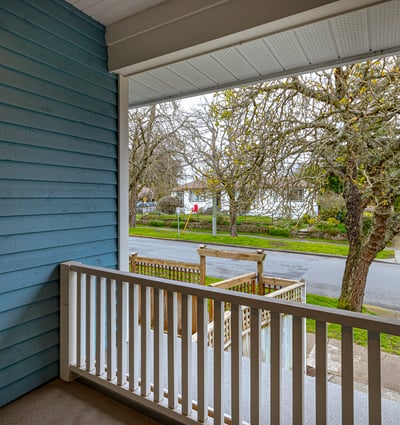Enjoy morning coffee on this inviting porch overlooking a tree-lined street in a peaceful neighborhood.