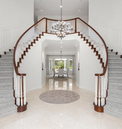 Grand foyer with dual staircases and a modern chandelier, creating an impressive first impression.