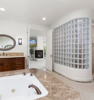 Primary Bathroom-Luxurious bathroom featuring a jetted tub, modern glass block shower, and ample natural light.