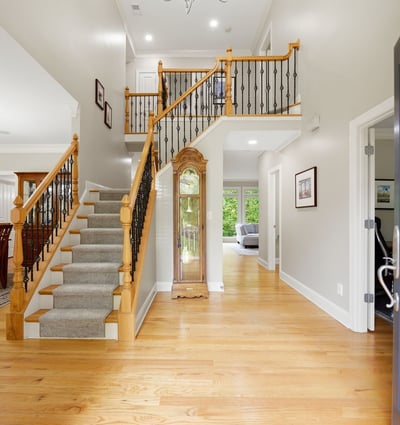 Bright and inviting entryway featuring a spacious layout, hardwood floors, and a sweeping staircase.