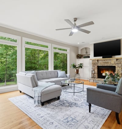 Bright and inviting living room featuring large windows, cozy fireplace, and spacious layout for entertaining.