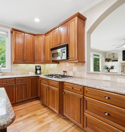 This spacious kitchen features rich cabinetry, granite countertops, and ample natural light, perfect for culinary enthusiasts.