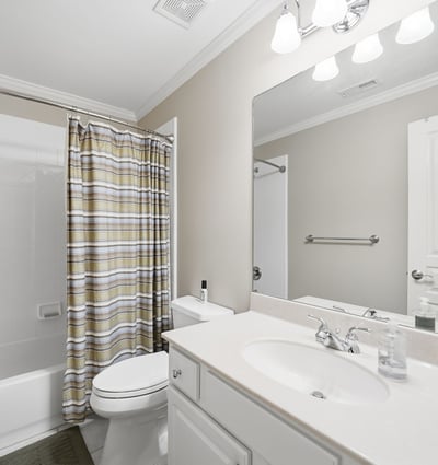 Bright and functional bathroom featuring a shower-tub combo, modern vanity, and ample storage options.