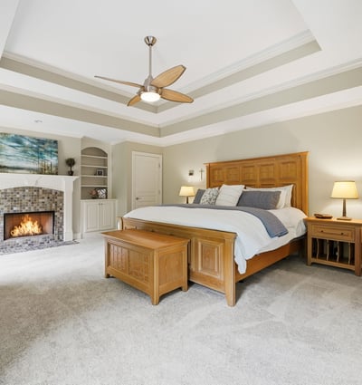 This spacious master bedroom features vaulted ceilings, a cozy fireplace, and ample built-in storage solutions.