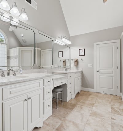 Spacious bathroom featuring dual vanities, modern fixtures, and abundant natural light from an arched window.