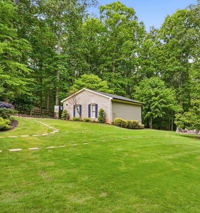Nestled among lush trees, this property features expansive green space and a versatile outbuilding.