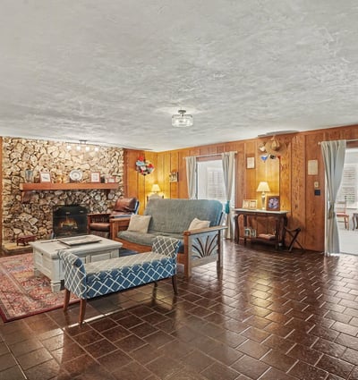Living Room with large river rock, wood burning fireplace and gorgeous pecky cypress accent walls!