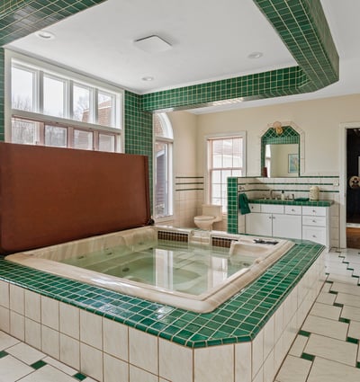 Spacious bathroom featuring a sunken tub, vibrant green tiles, and ample natural light throughout.