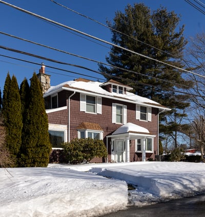 Spacious two-story home surrounded by trees, featuring ample outdoor space and winter scenery.