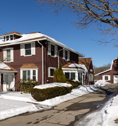Spacious four-bedroom home with inviting exterior, expansive driveway, and a large garage on a snowy lot.
