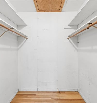 Spacious walk-in closet features ample hanging space, offering potential for organized storage solutions.