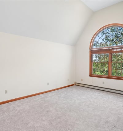 Bright, spacious room featuring a large arched window that offers abundant natural light and scenic views.