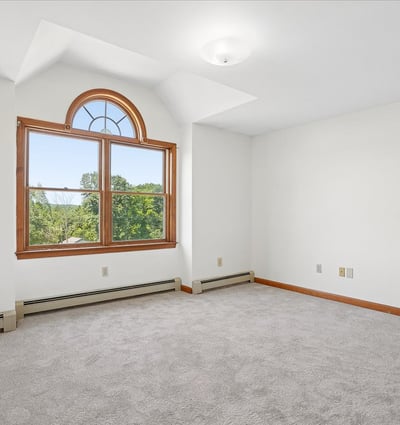 Bright and airy room featuring large windows and plush carpet, perfect for creative space or cozy retreat.
