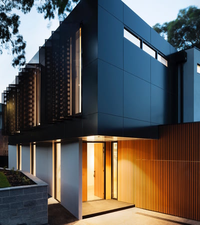 Modern architectural masterpiece featuring sleek lines, contrasting materials, and inviting entrance in a serene setting.