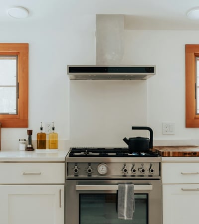 Modern kitchen featuring stainless steel appliances, wooden accents, and ample natural light through large windows.
