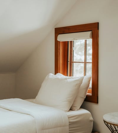 Cozy bedroom featuring natural light from a quaint window and minimalist decor for a peaceful atmosphere.