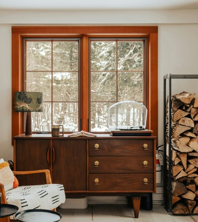 Bright and inviting space with natural light, featuring a cozy reading nook and rustic wood storage.