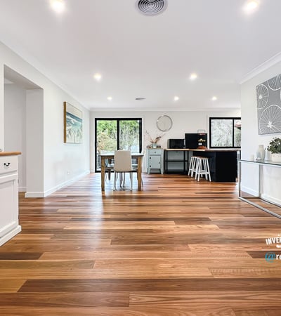 Spacious open-concept living area with warm wooden floors and abundant natural light, ideal for entertaining.