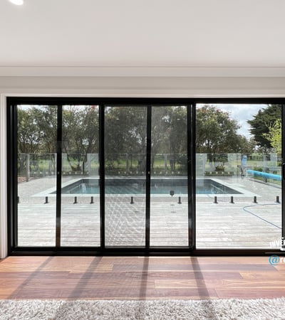 Bright and inviting living space with expansive glass doors opening to a private pool and outdoor deck.