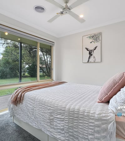Bright and airy bedroom with large windows offering stunning views of the lush backyard.