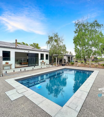This contemporary home features a spacious outdoor area with a pristine pool and landscaped surroundings.