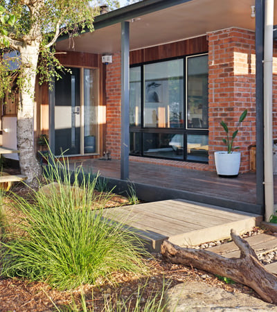 Contemporary home featuring expansive windows and an inviting outdoor space surrounded by lush greenery.