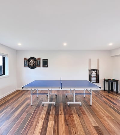 Bright recreational space featuring a ping pong table, arcade machine, and dartboard for entertainment.