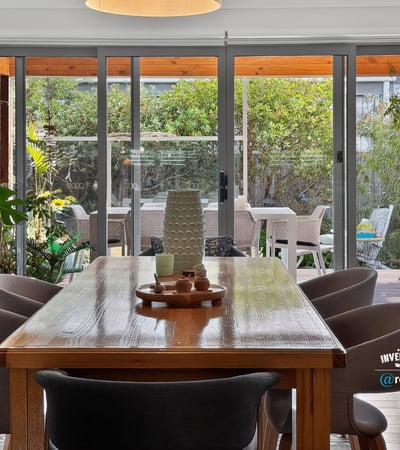 Bright dining area opens to a lush outdoor space, perfect for gatherings and entertaining.