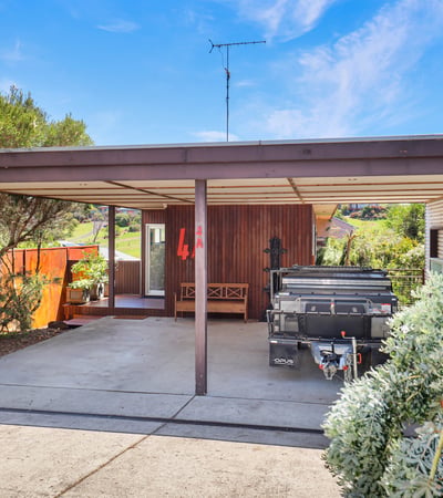 This property features a spacious carport, landscaped surroundings, and a unique architectural design, ideal for customization.