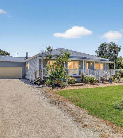 Spacious home with large yard, dual garages, and inviting porches, perfect for outdoor gatherings and relaxation.