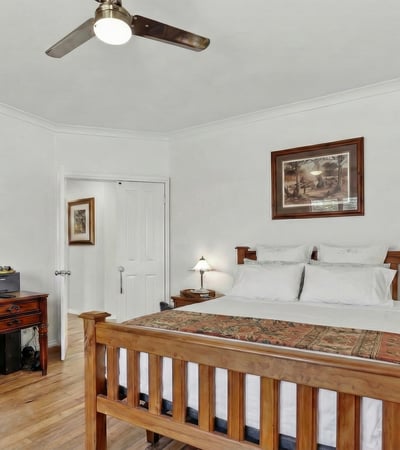 Bright and airy bedroom featuring a wooden bed frame and dedicated workspace, perfect for remote living.