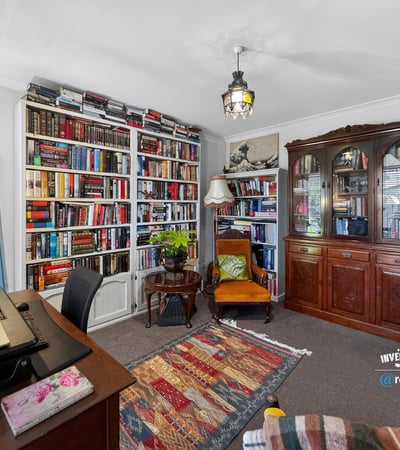 Cozy reading nook with expansive bookshelves and a versatile workspace, perfect for relaxation and productivity.