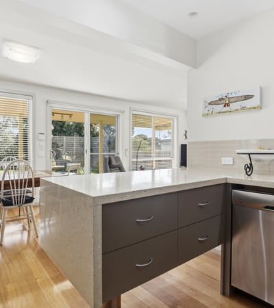 Bright and airy kitchen featuring modern finishes, large windows, and seamless access to outdoor dining.