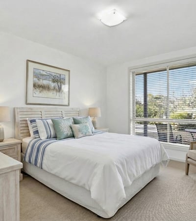 Bright and inviting bedroom featuring large windows, comfortable furnishings, and a relaxing atmosphere.