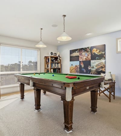 Bright recreation room featuring a pool table, ample natural light, and a cozy atmosphere for entertaining.