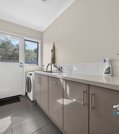 Bright laundry area featuring modern cabinets, ample counter space, and convenient outdoor access.