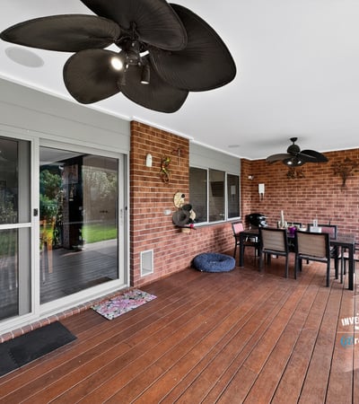 Spacious covered patio perfect for outdoor dining, featuring ceiling fans and a view of the lawn.