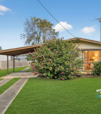 Cozy home featuring expansive green lawns and a covered carport, ideal for outdoor living.