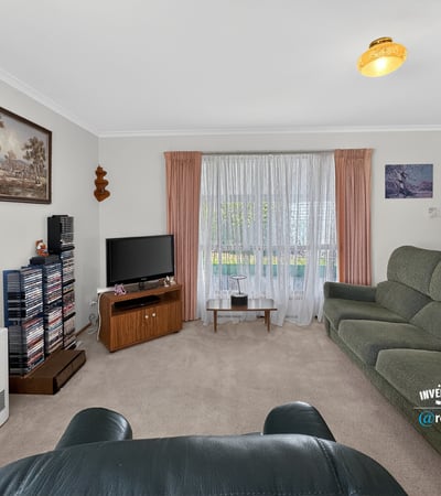 Spacious living room with large windows, offering ample natural light and a cozy atmosphere for gatherings.