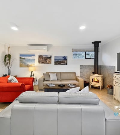 Spacious living area features comfortable seating and a cozy wood stove, perfect for relaxation and gatherings.
