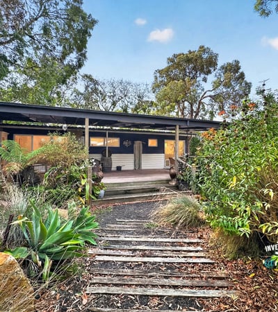 This inviting home features a spacious front porch and lush gardens, perfect for outdoor relaxation.