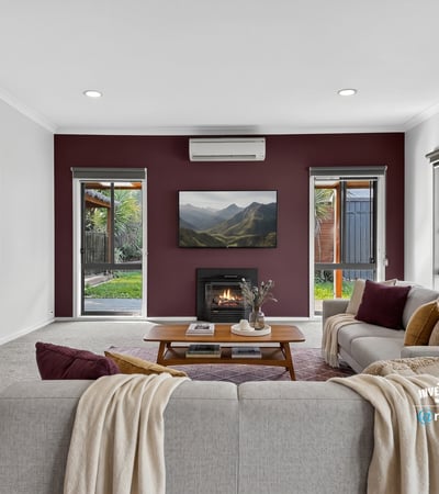 Cozy living room with modern features, featuring a fireplace and large windows overlooking a private outdoor space.