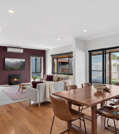 Bright and inviting open-plan living space featuring large windows and a cozy fireplace. Perfect for gatherings.