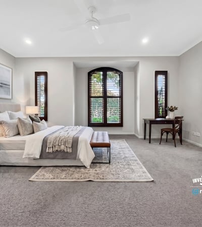 Spacious master bedroom featuring large windows, plush carpeting, and a cozy reading nook.