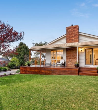 Nestled on a spacious lawn, this home features a welcoming porch and abundant outdoor greenery.