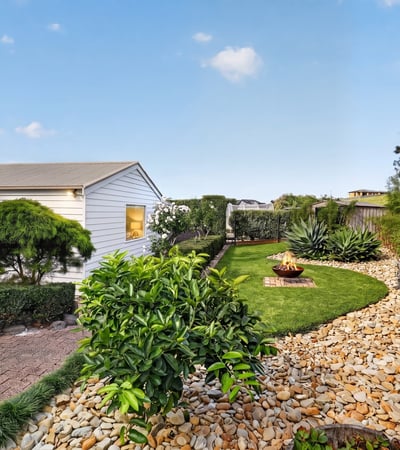 Discover a tranquil outdoor space featuring neat landscaping, unique planting beds, and a cozy fire pit area.