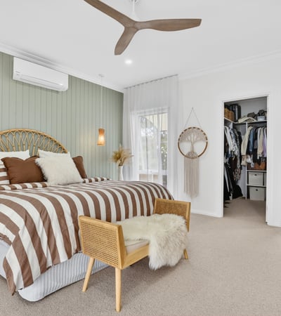 Spacious bedroom featuring unique decor, natural light, and convenient access to an organized closet and bathroom.