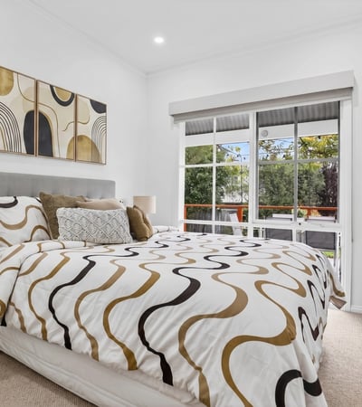 Bright bedroom featuring large windows, modern decor, and a cozy layout, ideal for relaxation and rest.